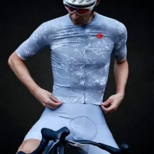 Ciclista con maillot y culotte de ciclismo gris junto a una bicicleta de carretera